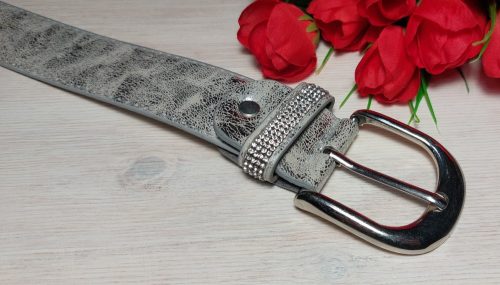 Női öv- Ezüst színű, bőrhatású női öv, strasszkövekkel díszített bújtatóval 37mm.